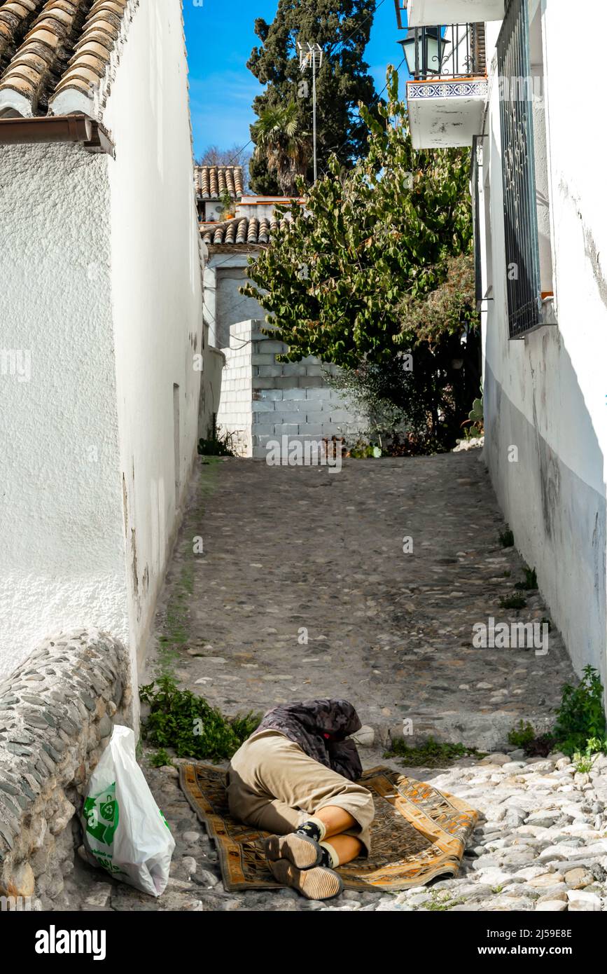Obdachloser, der mitten in der engen Straße im Zentrum von Granada, Andalusien, schläft Stockfoto