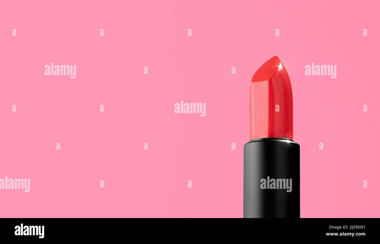 Ein leuchtend roter Lippenstift in einem schwarz-matten Etui auf einem rosa Hintergrund. Dekorative Kosmetik auf einem leuchtend rosa Hintergrund. Gesichtskosmetik, Mode, Make-up. Stockfoto