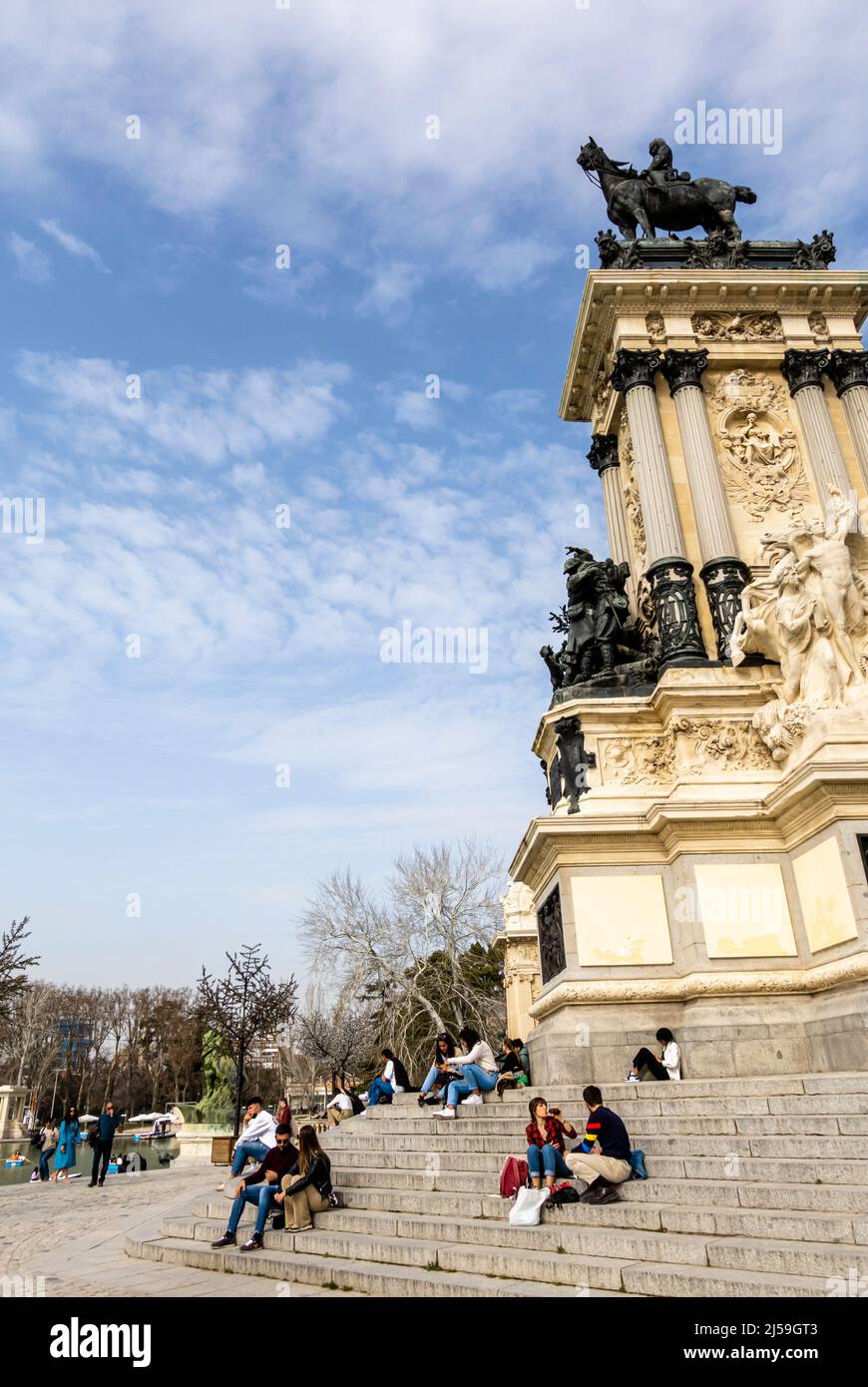 Jugendliche Touristen sitzen in der Nähe von Teich im El Retiro Park, Madrid, Spanien Stockfoto