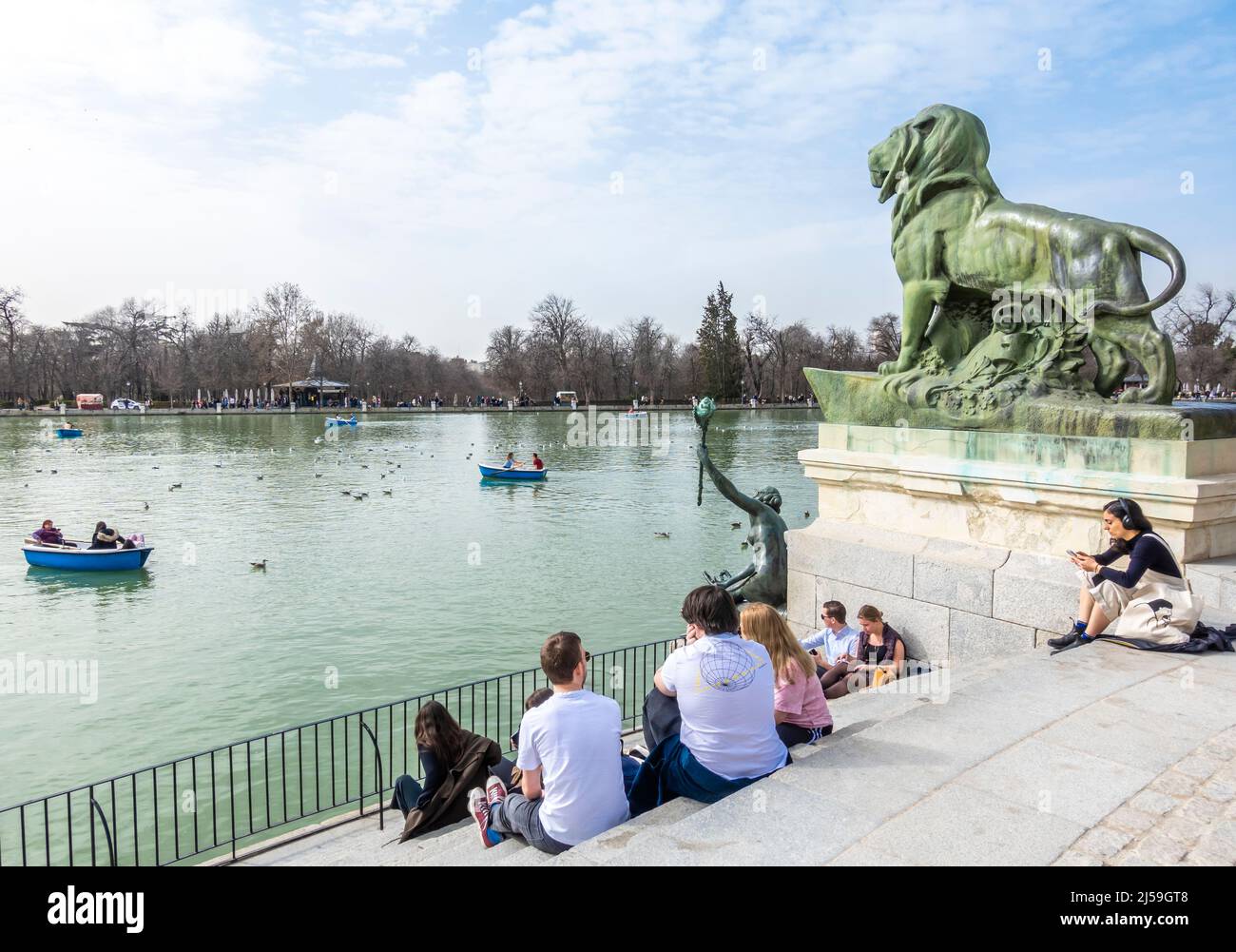 Jugendliche Touristen sitzen in der Nähe des Teichs im El Retiro Park, Madrid, Spanien Stockfoto