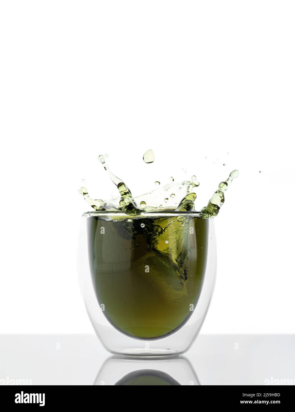 Glas Wasser mit Chlorophyll-Extrakt vor weißgrauem Hintergrund. Flüssiges Chlorophyll in einem Glas Wasser mit Spritzer. Konzept von Superfood Stockfoto