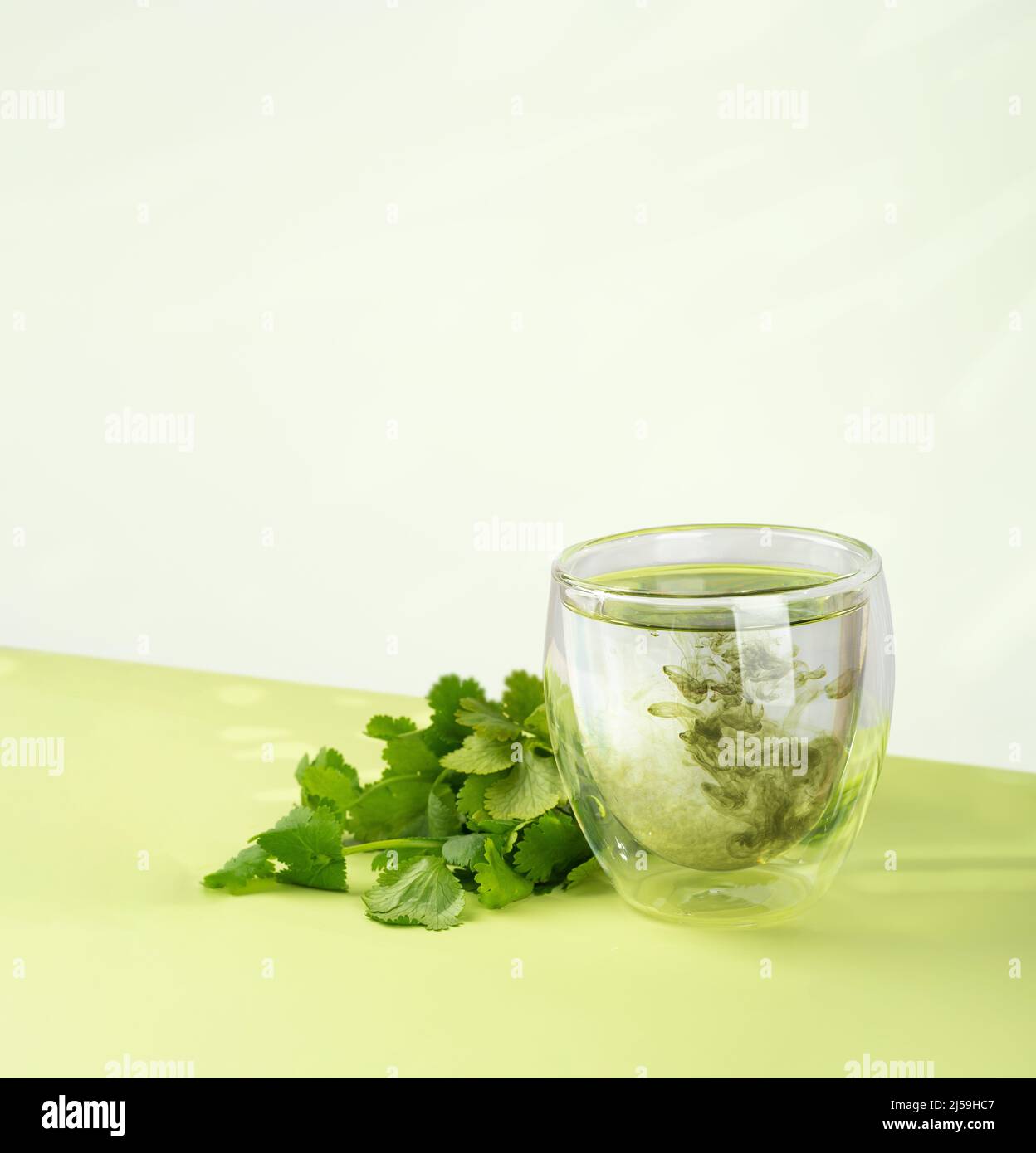 Glas Wasser mit flüssigem Chlorophyll und frischen Kräutern auf einem grünen Tisch. Konzept von Superfood, gesunde Ernährung, Entgiftung und Ernährung. Grüner Hintergrund Stockfoto