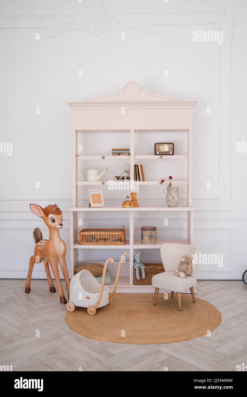 Stilvolles skandinavisches neugeborenes Babyzimmer mit Spielzeug, Kinderstuhl. Moderne Einrichtung mit grauen Hintergrundwänden Stockfoto