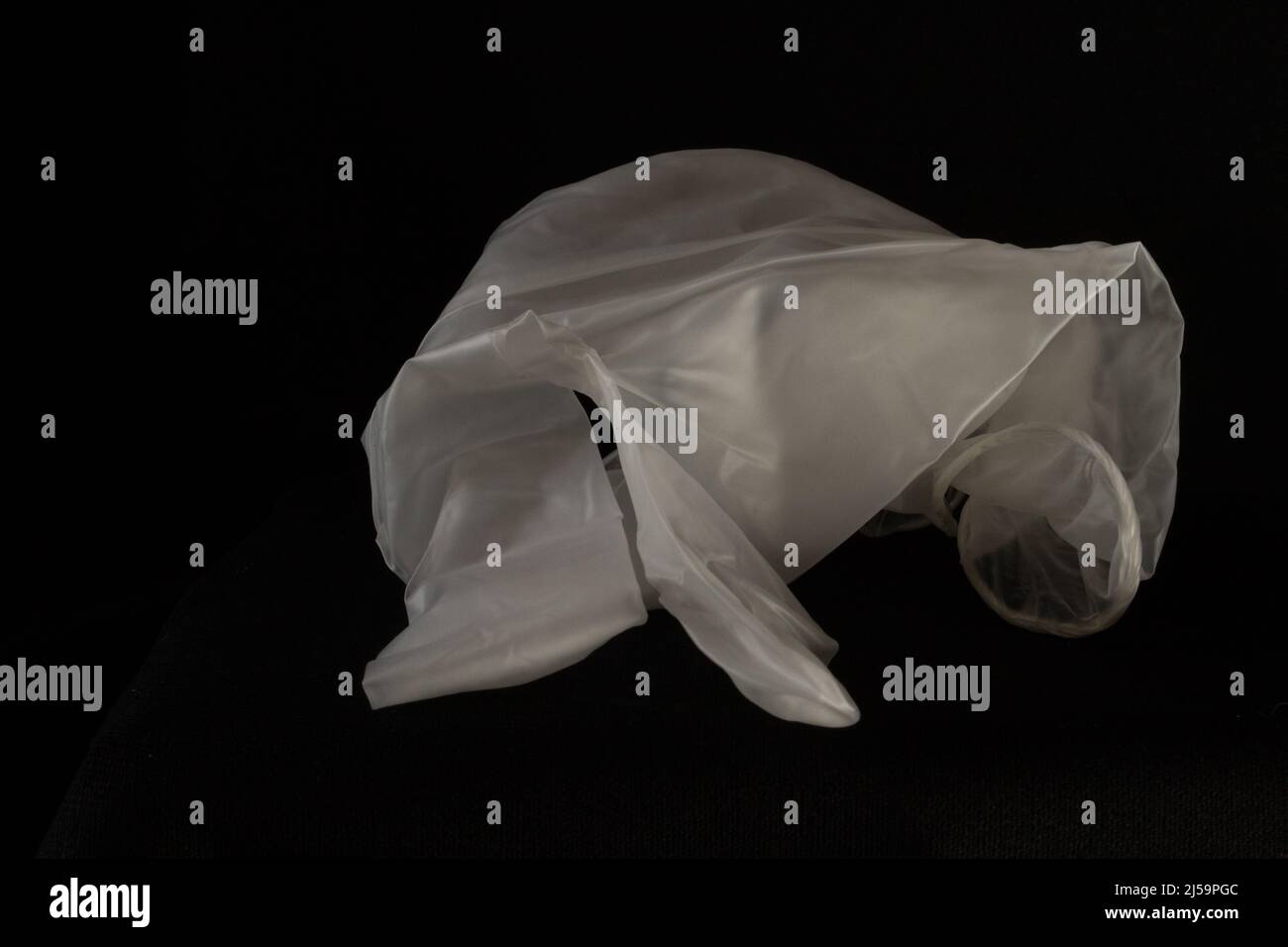 Weißer Einweghandschuh mit 2 Fingern, isoliert auf schwarzem Hintergrund Stockfoto