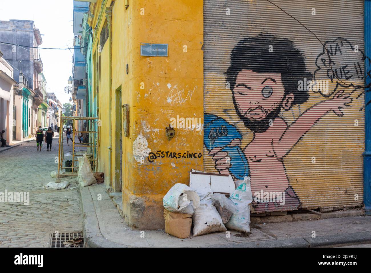 Müllsäcke in einer Ecke der Altstadt von Havanna. Ein urbanes Graffiti-Gemälde ist in einer alten metallischen vertikal Schiebetür eines Unternehmens zu sehen. Stockfoto