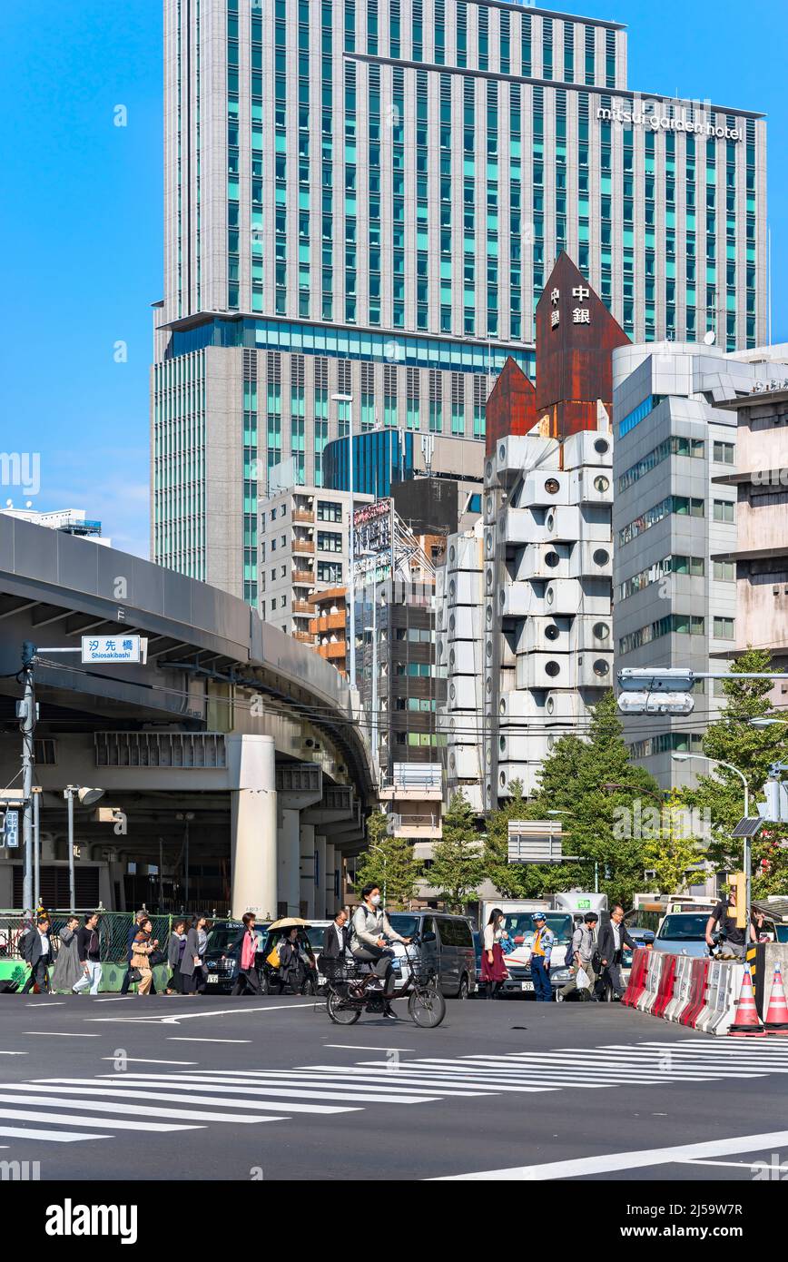 tokio, japan - oktober 28 2019: Japaner gehen auf Fußgängerüberwegen vor dem legendären Nakagin Capsule Tower Gebäude, das 70' AS errichtet wurde Stockfoto