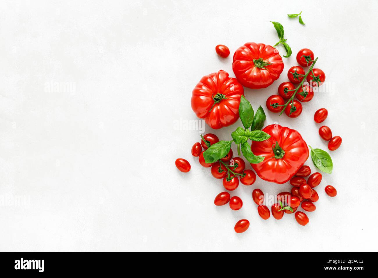 Tomaten und Basilikum auf weißem Hintergrund, Draufsicht, flach liegend Stockfoto