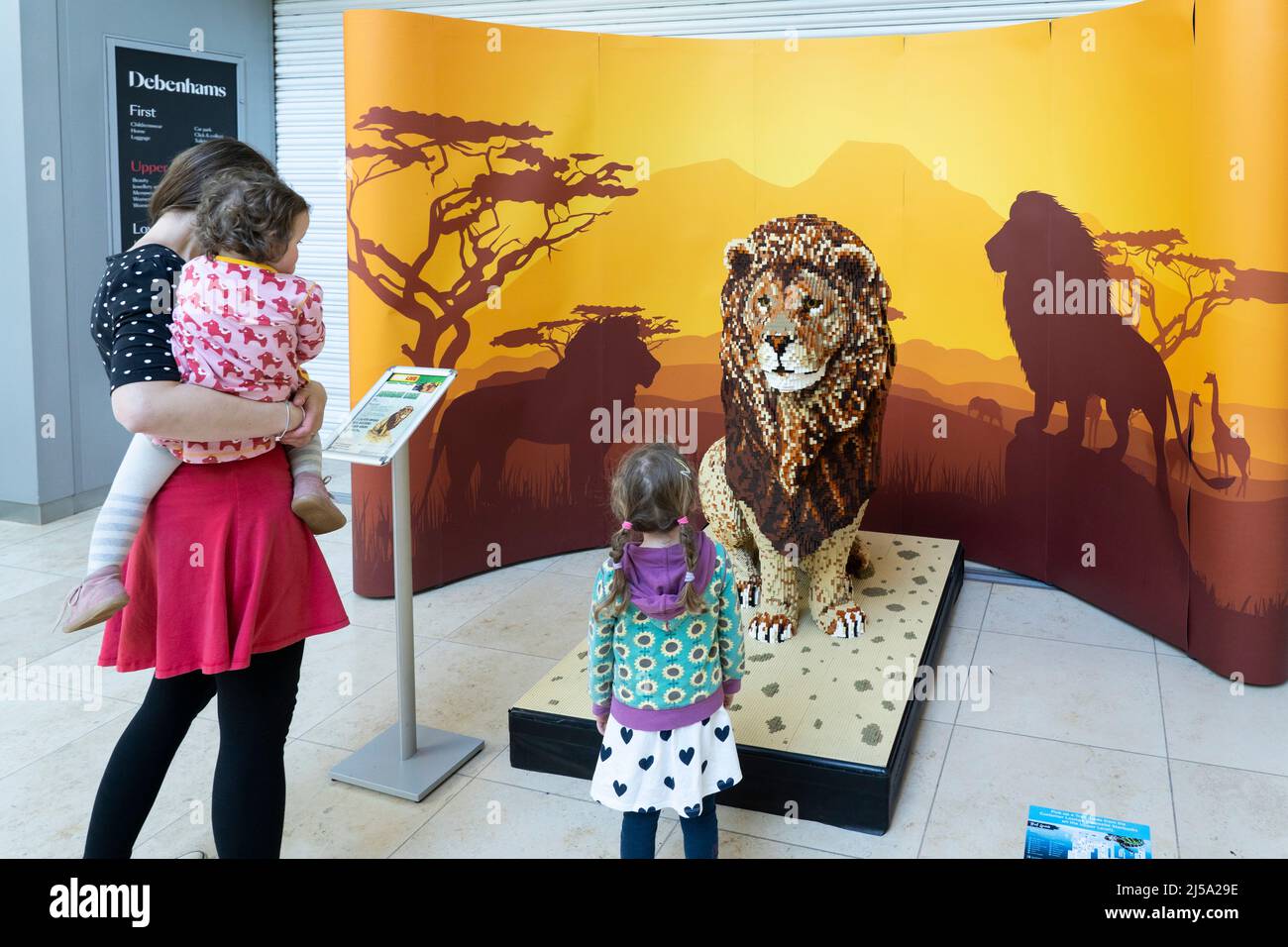 Mutter und ihre Töchter betrachten ein Modell eines afrikanischen Löwen, Teil des Brick Live Animal Paradise Events im April im Festival Place, Basingstoke. VEREINIGTES KÖNIGREICH Stockfoto