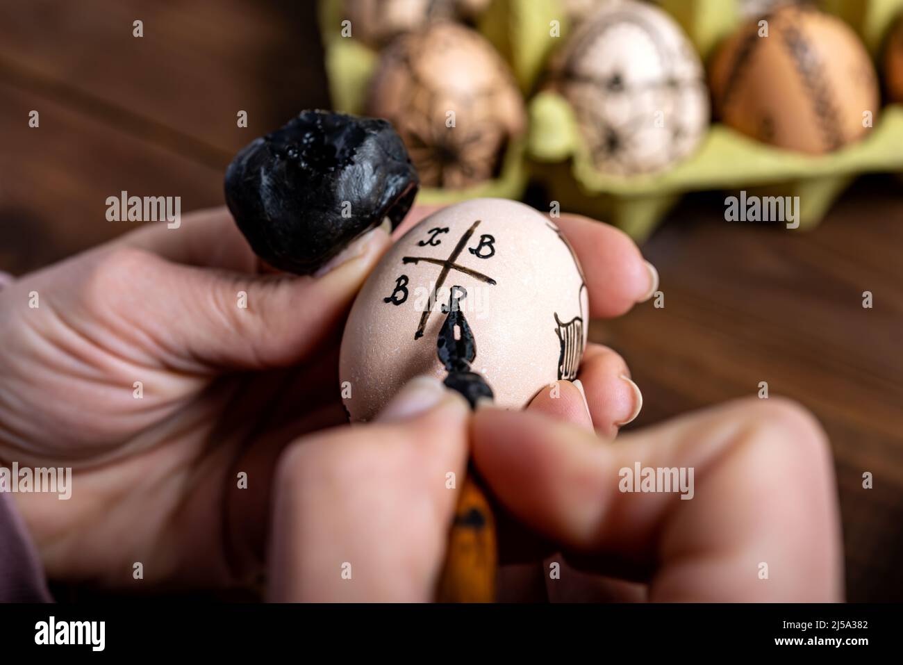 Weibliche Hände malen traditionell Eier mit einem Füllfederhalter und Wachs zu Ostern. Ostervorbereitungskonzept. Stockfoto