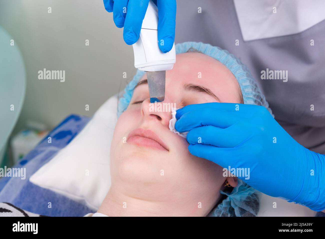 Ultraschallpeeling im Gesicht. Junge Frau bekommt Ultraschallhaut mit Hautschrubber in der Kosmetikklinik. Stockfoto