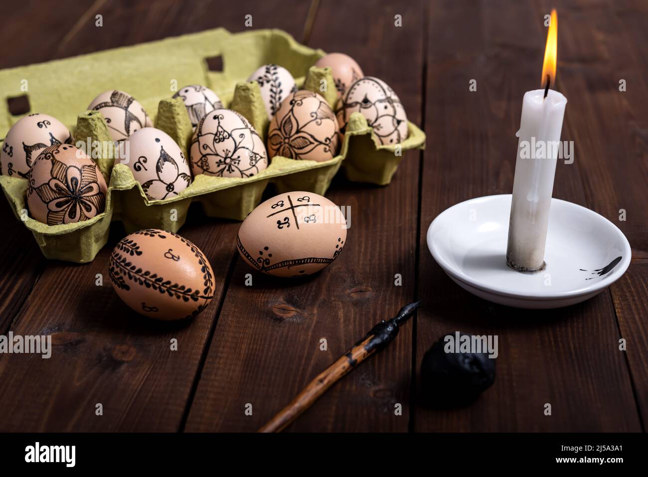 Traditionell bemalte Ostereier mit einem Füllfederhalter und Wachs in einer Verpackung, die zum Kochen und Färben auf einem Holztisch bereit ist. Ostern Vorbereitung conce Stockfoto