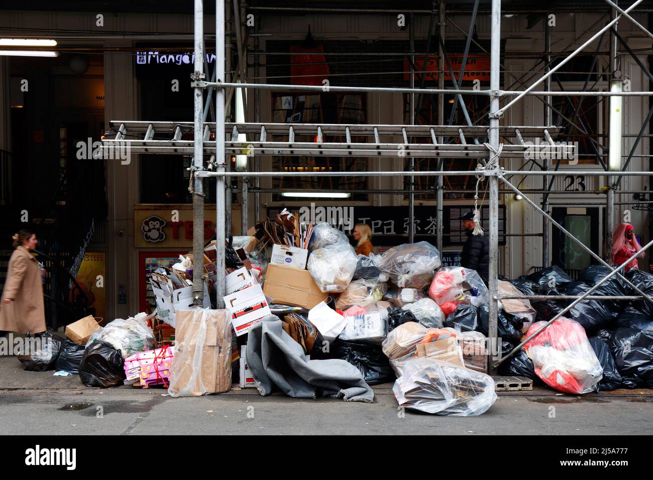 Kommerzieller und Haushaltsmüll am Straßenrand stapelten sich unter einem Gehsteig, einem Gehsteig-Gerüst auf einem Bürgersteig in New York City im East Village Stockfoto