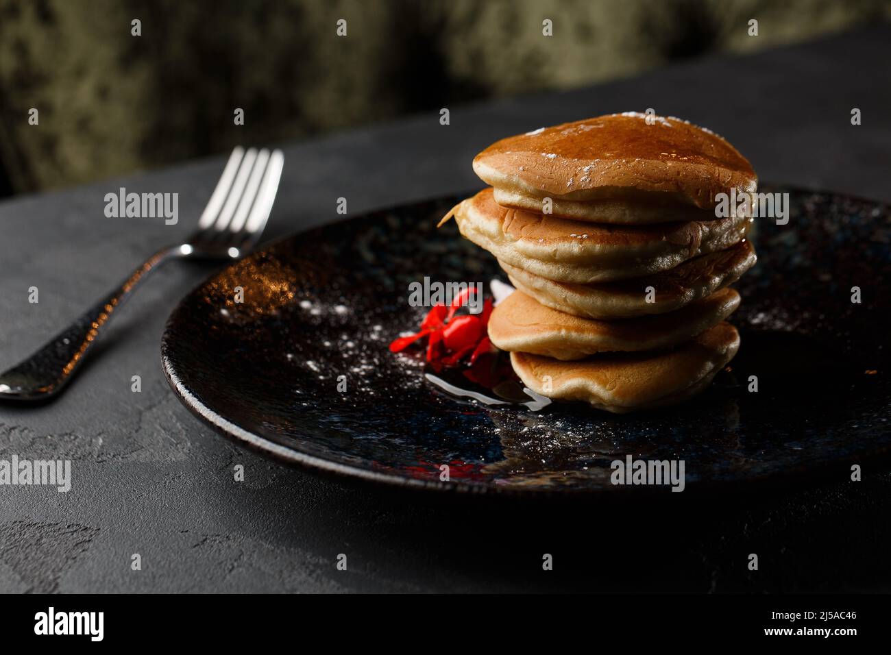 Amerikanische Pfannkuchen mit Beeren und Ahornsirup auf schwarzem ...