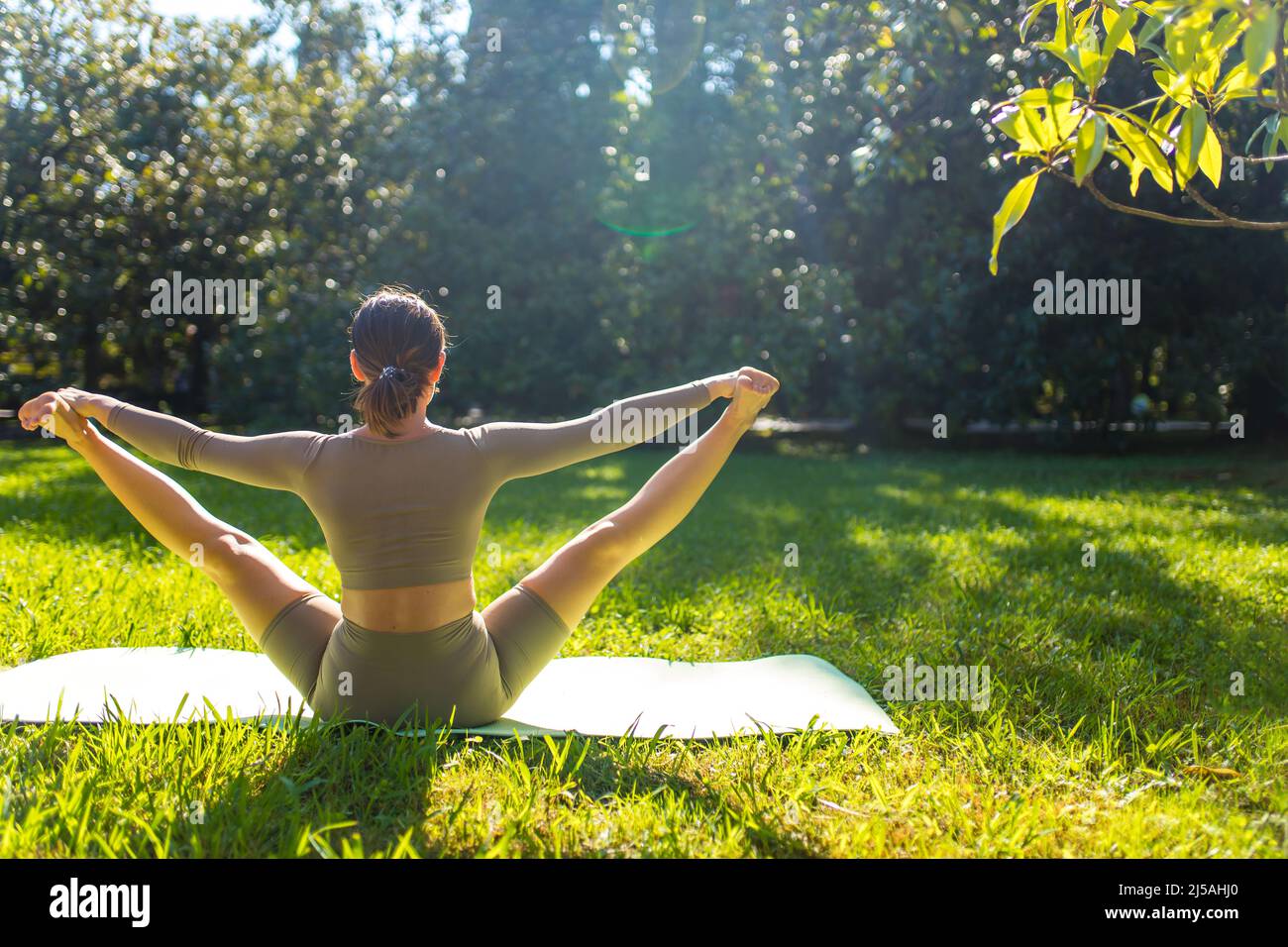 Frau, die morgens im tropischen Park Akro-Yoga-Übungen macht Stockfoto