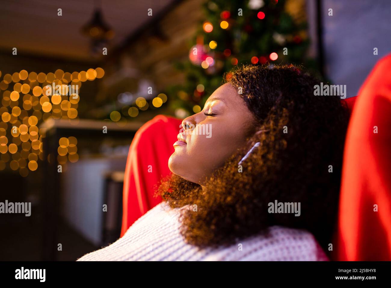 Ruhige junge Frau schloss die Augen entspannt lehnte sich auf Couch moderne kabellose Kopfhörer in einem Ohrkissen Stockfoto