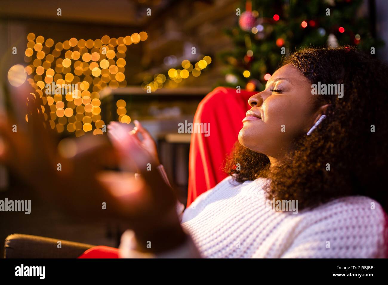 Ruhige junge Frau schloss die Augen entspannt lehnte sich auf Couch moderne kabellose Kopfhörer in einem Ohrkissen Stockfoto