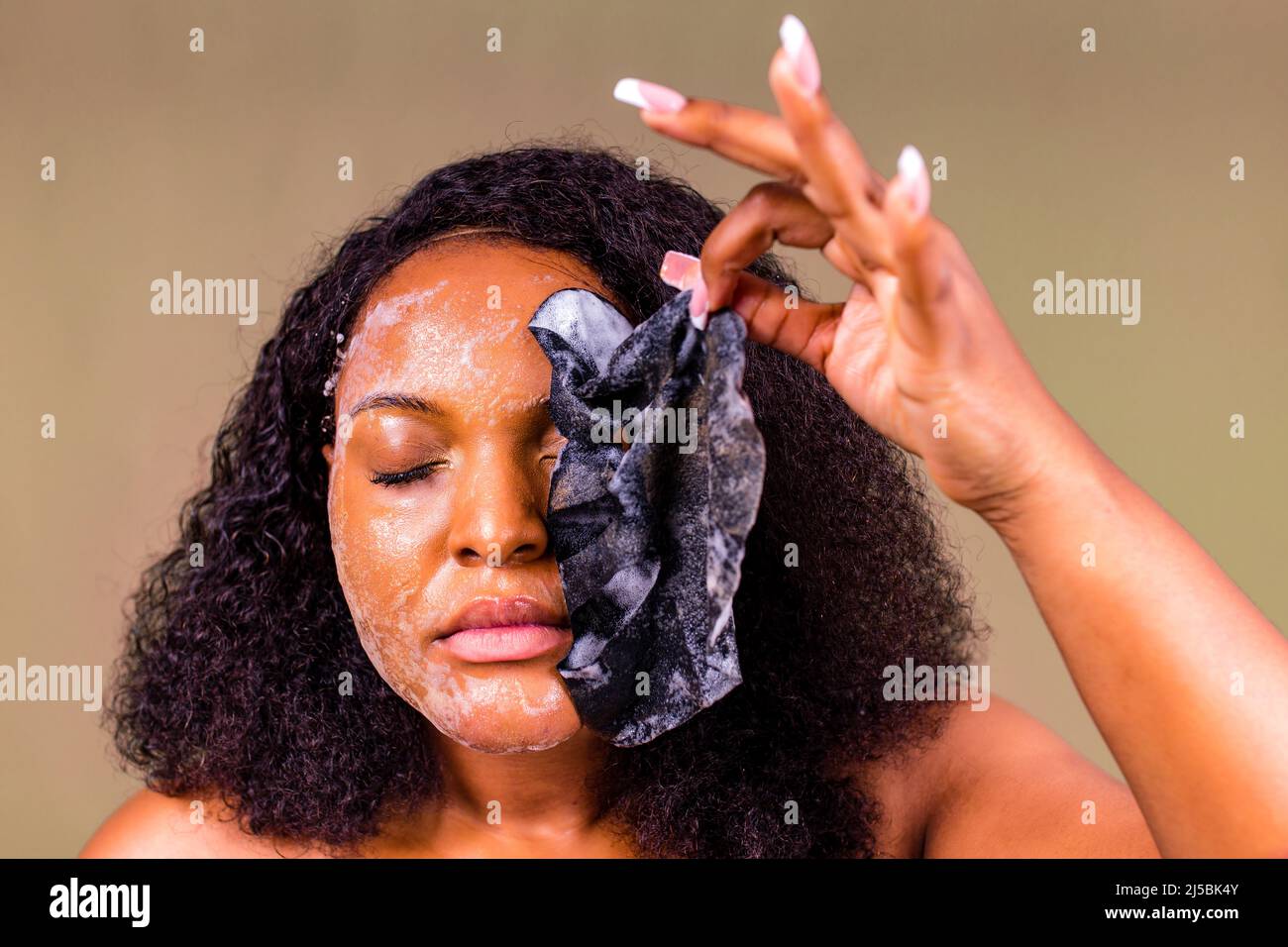Junge Frau mit Blasenblatt Maske auf ihrem Gesicht auf braunem Hintergrund Stockfoto
