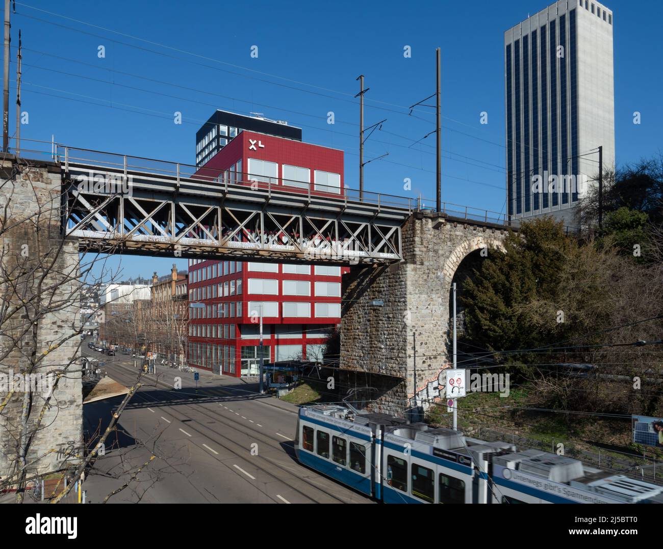 Zürich, Schweiz - März 5. 2022: Eine Trambahn, die unter einer Eisenbahnbrücke in einem Geschäftsviertel fährt Stockfoto
