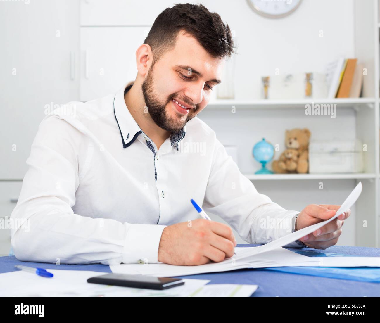 Lächelnder junger Mann, der eine profitable Finanzvereinbarung unterzeichnet Stockfoto