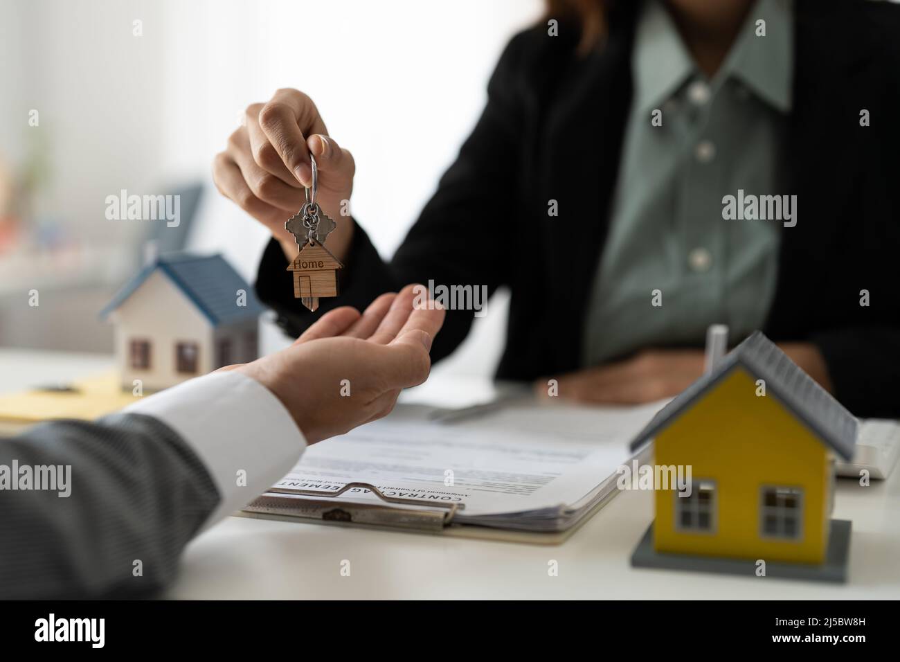 Immobilienmakler hält Hausschlüssel an seinen Kunden nach Unterzeichnung Vertrag im Büro, Konzept für Immobilien, Umzug oder Vermietung von Immobilien Stockfoto