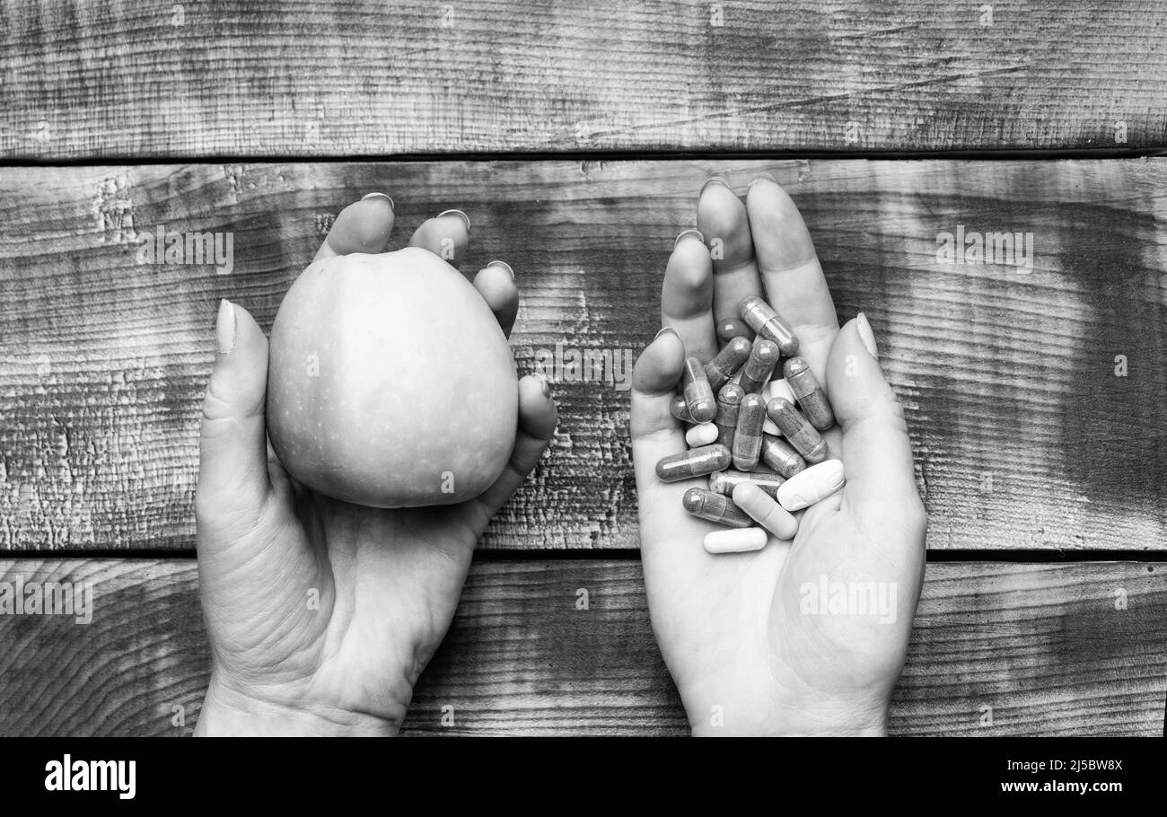 Apfel natürliche Lebensmittel und Nahrungsergänzungsmittel in Kapseln in weiblichen Händen hölzernen Hintergrund, Vitamine Stockfoto