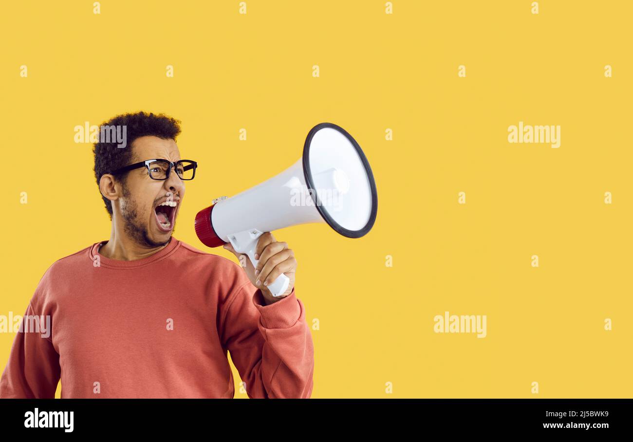 Witziger verrückter männlicher Student, der eine laute Ankündigung macht, indem er in seinem Megaphon schreit Stockfoto