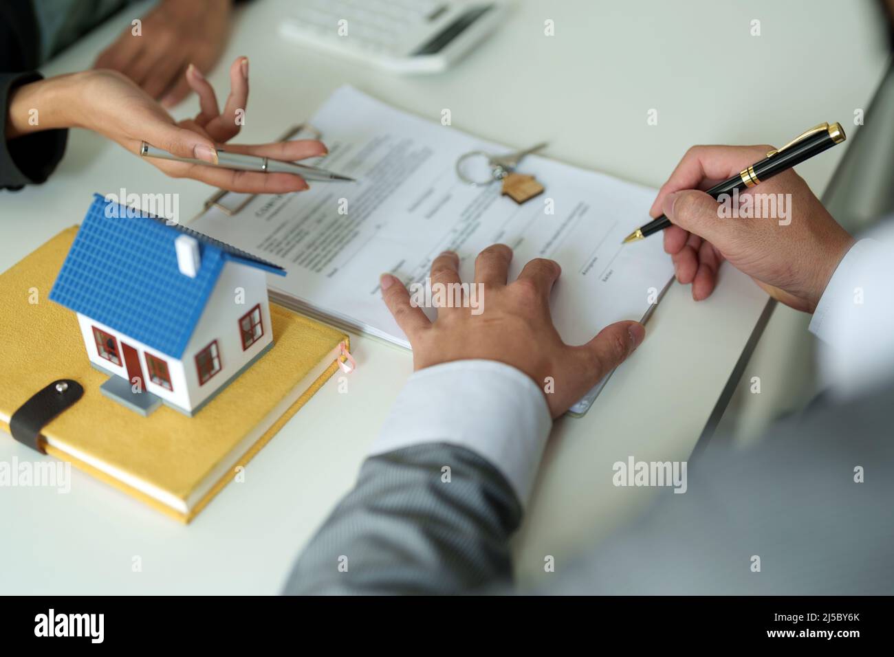 Immobilienmakler stimmen zu, ein Haus zu kaufen und geben den Kunden Schlüssel in den Büros ihrer Agentur. Konzeptvereinbarung Stockfoto