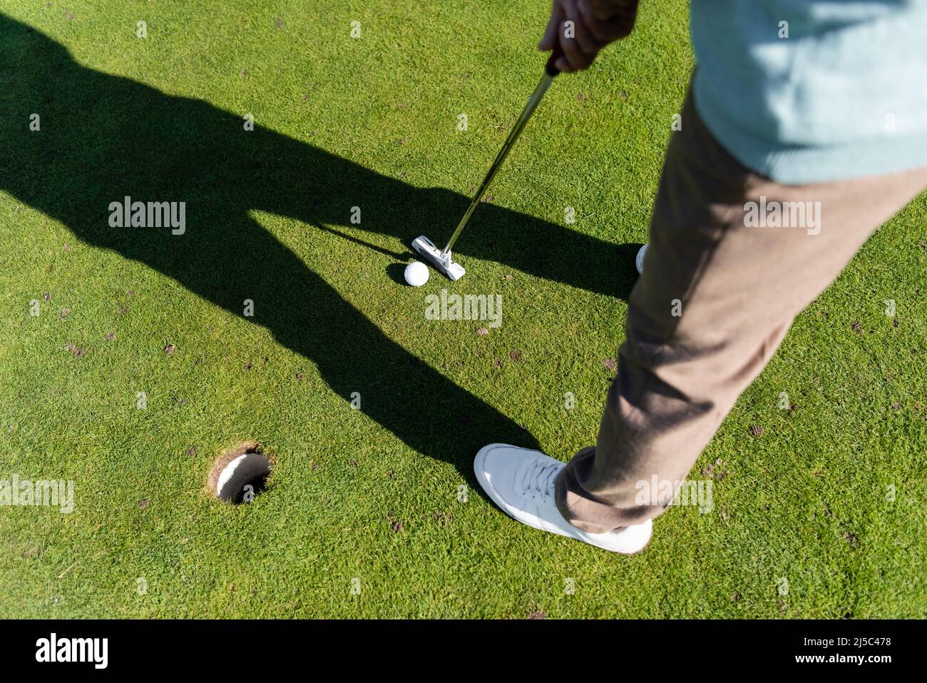 Draufsicht des Mannes in weißen Sneakers, der Golf auf dem Rasen spielt, Banner Stockfoto