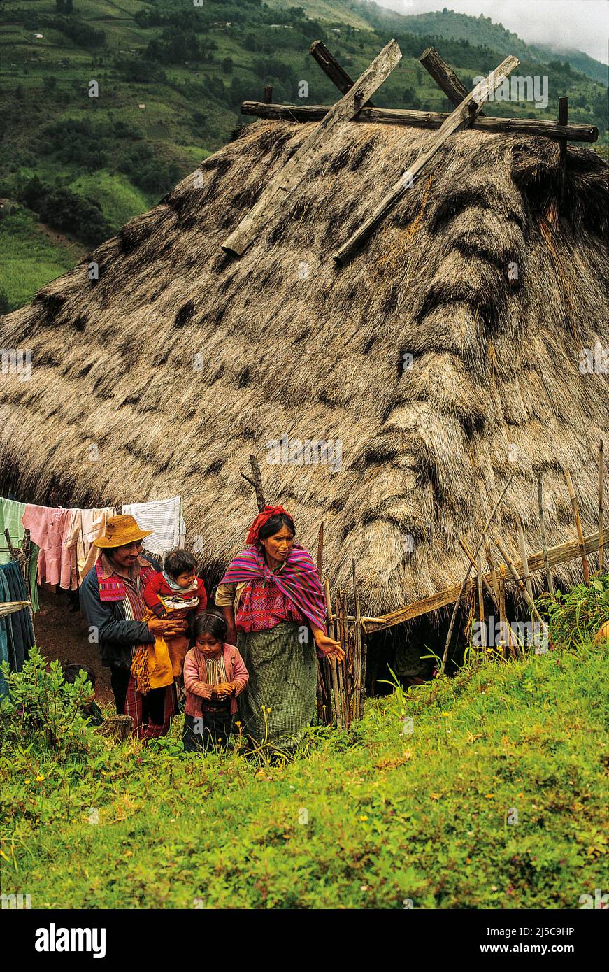 Eine Maya-Familie vor einer strohgedeckten Hütte in Todos Santos Cuchumatán, in der Sierra de los Cuchumatanes, Guatemala, Mittelamerika. © Kraig Lieb Stockfoto