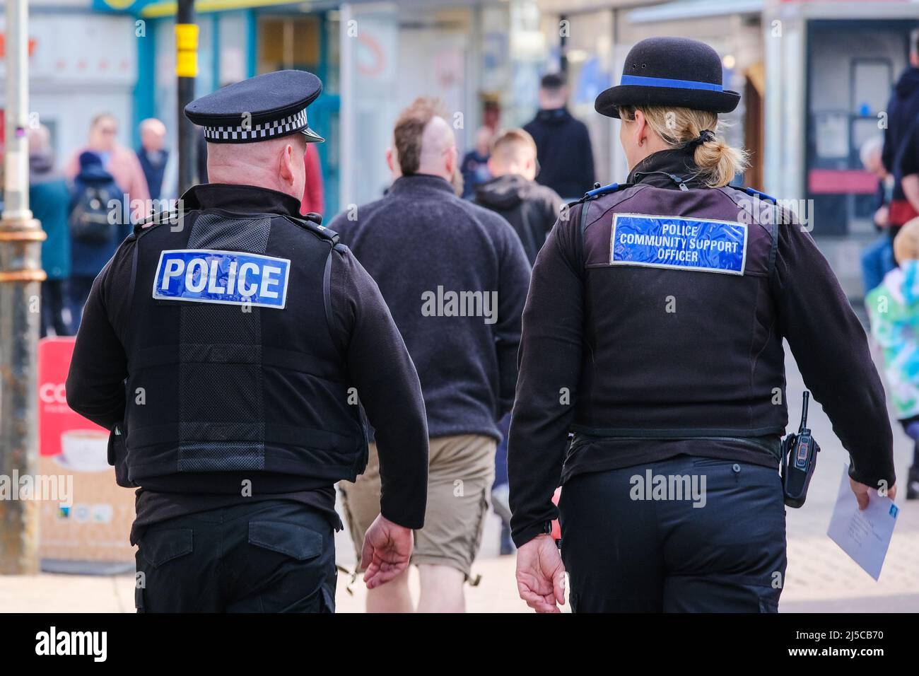 Ein Polizeibeamter und ein Unterstützungsbeamter der Polizeigemeinde, die durch das Stadtzentrum von Newquay in Cornwall im Vereinigten Königreich gehen. Stockfoto