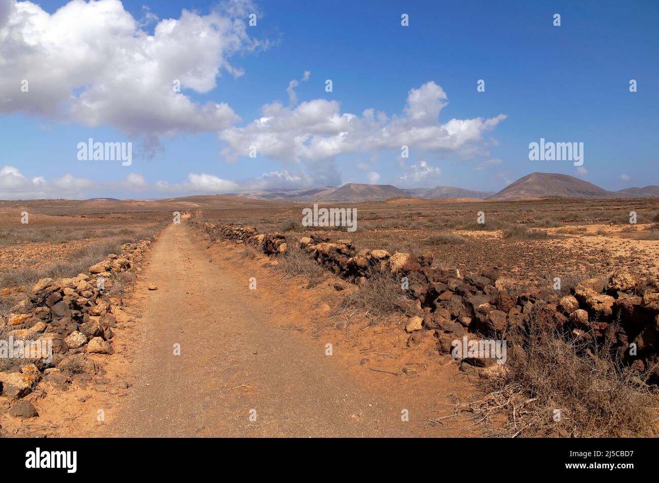 Sehr gerader langer, staubiger Pfad durch die vulkanische Landschaft von Lanzarote in Richtung des fernen Horizonts, in der Nähe von Costa Teguise. Februar 2022 Stockfoto