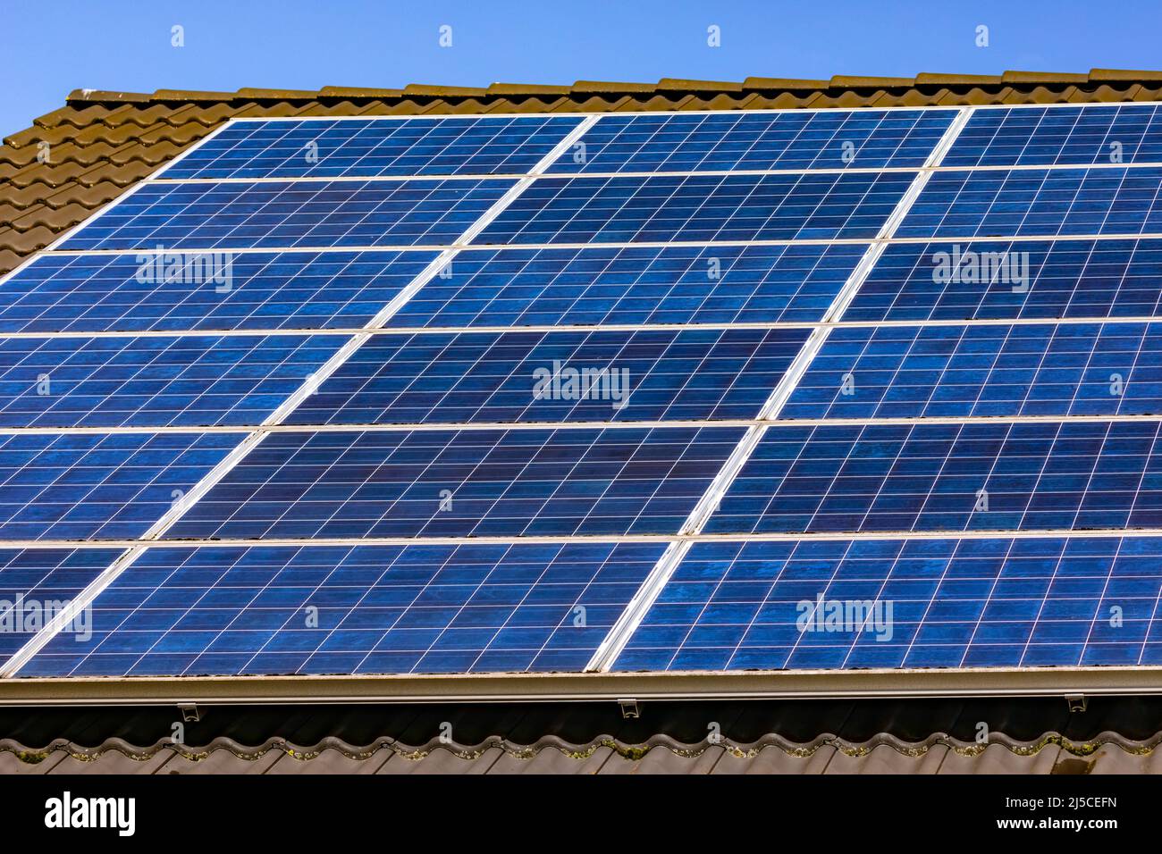 Solarzellen einer privaten Photovoltaikanlage auf einem Dach in Deutschland ermöglichen die Energiewende Stockfoto