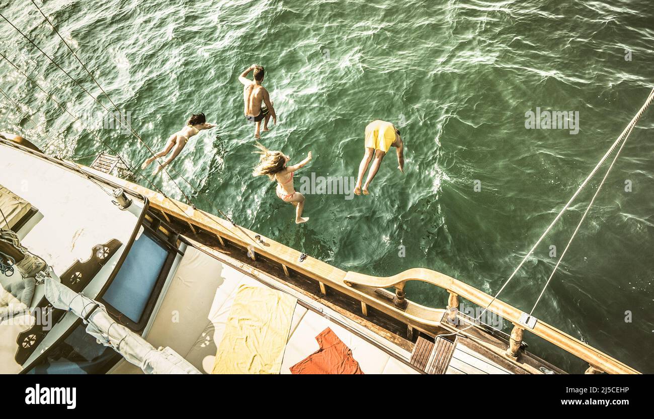 Luftaufnahme der jungen Leute, die auf einem Seetrip vom Segelboot springen - reiche glückliche Freunde, die im Sommer Spaß am Segelbootparty haben - Exklusive Luxusvaca Stockfoto