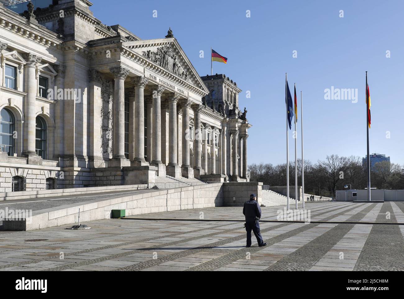 Ein Polizist vor dem geschlossenen Reichstag in Berlin. Wo normalerweise viele Hunderte von Menschen den Regierungsbezirk besuchen, herrscht jetzt ein unheimliches Schweigen. Das öffentliche Leben in Berlin ist nach den jüngsten Schutzmaßnahmen gegen die Ausbreitung des Corona-Virus praktisch zum Stillstand gekommen. Betroffen sind alle Sehenswürdigkeiten, Museen, Plätze, Straßen, Restaurants, Universitäten. [Automatisierte Übersetzung] Stockfoto