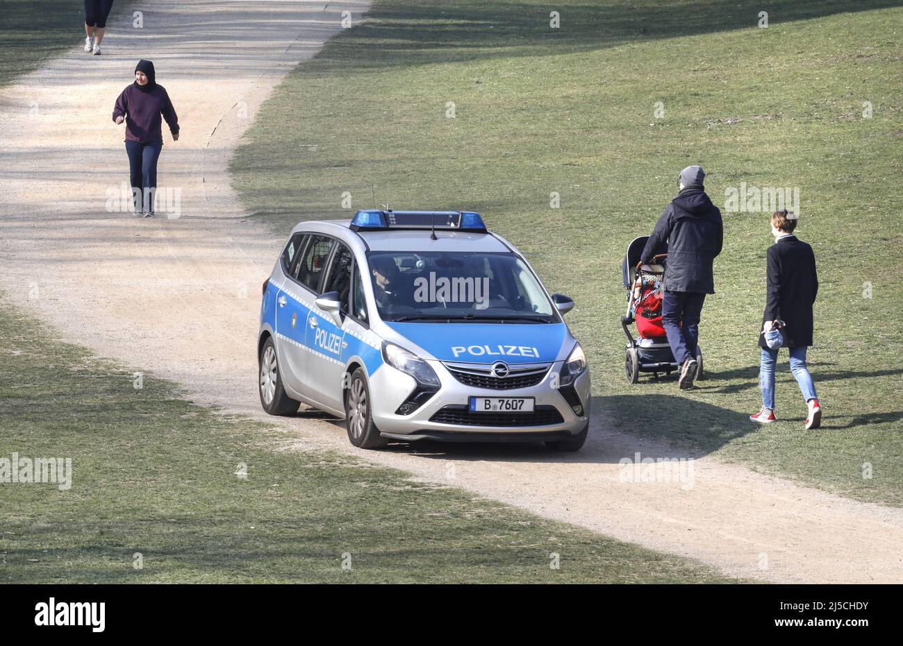 Polizisten fahren mit einem Polizeiauto durch einen Berliner Park. Die Polizei überprüft Parks auf Einhaltung des Kontaktverbots von Corona. Berliner dürfen das Frühlingswetter nur unterwegs genießen [automatisierte Übersetzung] Stockfoto