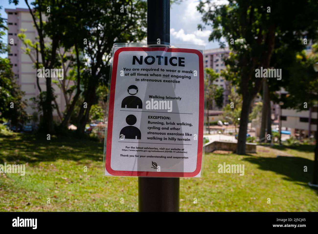 04/22/2020, Singapur, Republik Singapur, Asien - Ein Schild über Covid-19 hängt an einem Laternenpfosten und weist auf verbindliche Maßnahmen hin, um die Ausbreitung des Coronavirus weiter zu begrenzen. Mit Ausnahme von körperlich anstrengenden Aktivitäten wie Radfahren oder Joggen muss jeder bei Verlassen seines Zuhauses und im Freien oder in der Öffentlichkeit jederzeit einen Mundschutz tragen. [Automatisierte Übersetzung] Stockfoto