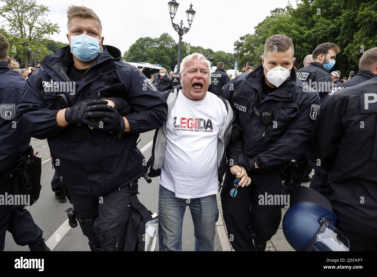 „Ein Mann, der ein Legida-Hemd trägt, wird während einer rechtsextremen Anti-Corona-Beschraenkungs-Demo von der Polizei verhaftet. Die Demonstration der rechten Extremisten wurde unter dem Motto "Heimat- und Weltfrieden" registriert. [Automatisierte Übersetzung]' Stockfoto