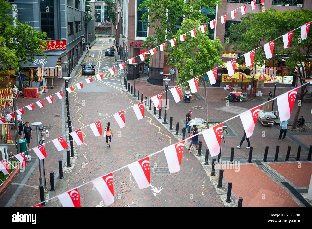 16.07.2020, Singapur, Republik Singapur, Asien - erhöhte Ansicht von kleinen Flaggen in den Nationalfarben des Stadtstaates, die als Wimpelfäden über eine Straße flattern, aufgehängt, um den bevorstehenden Nationalfeiertag am 9. August zu markieren. Aufgrund der anhaltenden Corona-Krise findet die diesjährige nationale Parade in einem viel kleineren Rahmen statt. [Automatisierte Übersetzung] Stockfoto