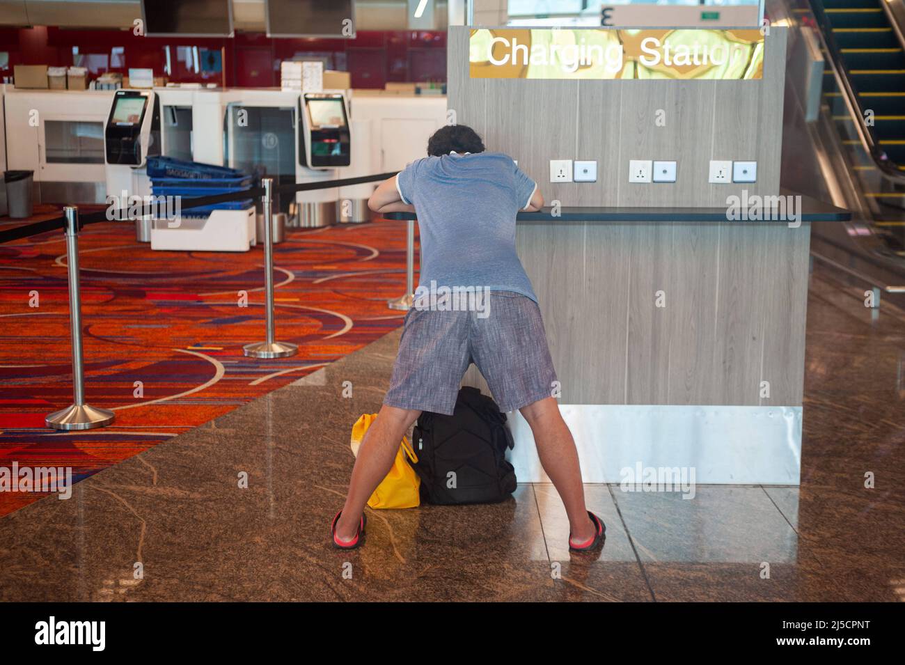 30.07.2020, Singapur, Republik Singapur, Asien - ein Fluggast steht an einer Ladestation für mobile Geräte im Terminal 1 am Changi Airport. Die weltweite Ausbreitung des Coronavirus (Covid-19) hat die Flugreisen weltweit drastisch reduziert und zu erheblichen Flugausfällen geführt. Aufgrund der Korona-Krise schrumpfte die Wirtschaft Singapurs im zweiten Quartal dieses Jahres um mehr als 40 Prozent, und die südostasiatische Finanzmetropole rutschte mehr als ein Jahrzehnt lang erneut in die Rezession. [Automatisierte Übersetzung] Stockfoto