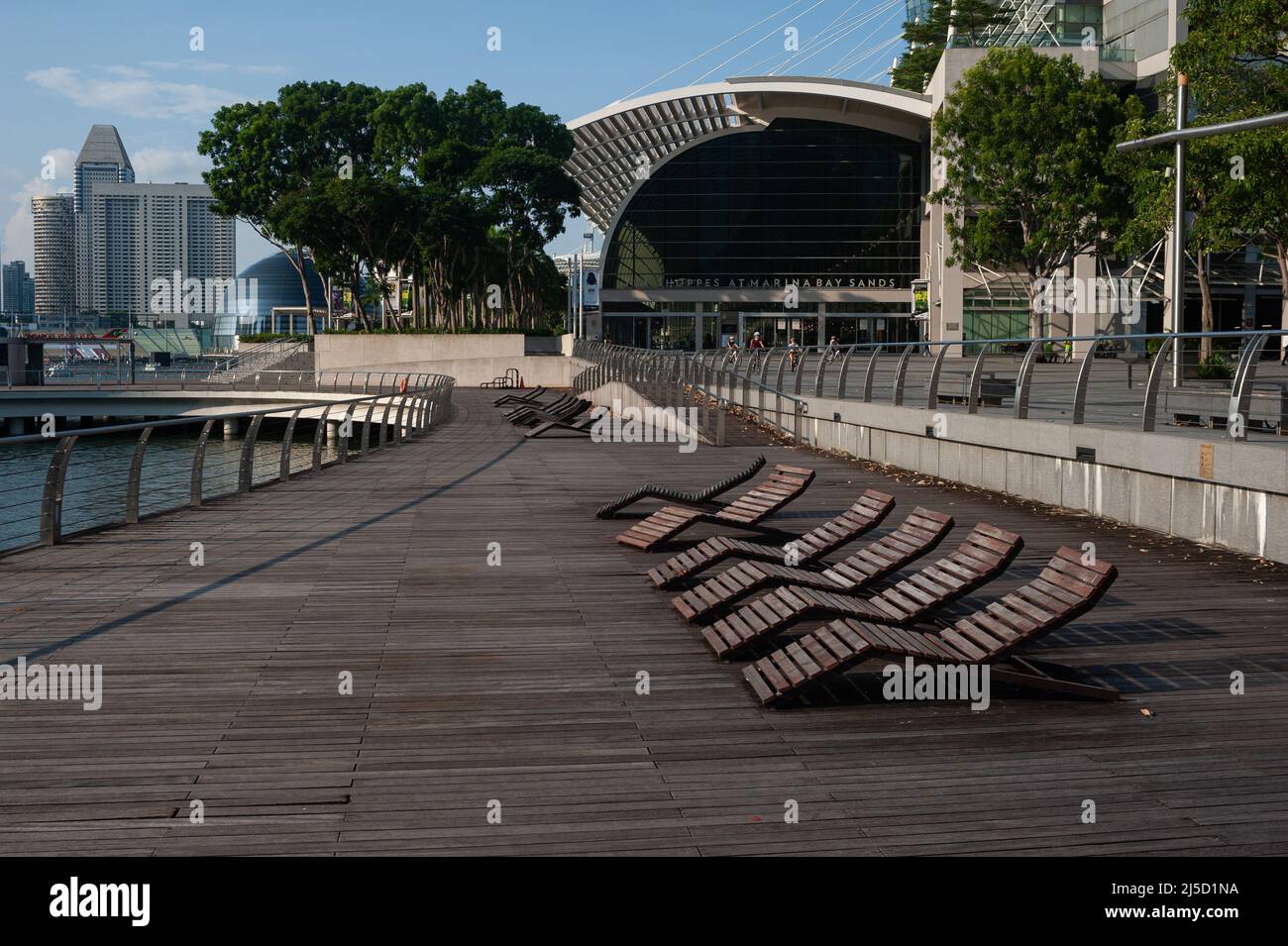 25.05.2021, Singapur, Republik Singapur, Asien - Leere Liegestühle am Wasser in Marina Bay während der anhaltenden Corona-Krise und des Shoppes-Einkaufszentrums in Marina Bay Sands im Hintergrund, kurz nachdem eine neue Infektionswelle das südostasiatische Land in einen Lockdown-ähnlichen Zustand zurückversetzt hat. Dies führte zu weiteren Einschränkungen wie strengeren Grenzmaßnahmen und Einreisebestimmungen, verbunden mit obligatorischen Vortests und einem negativen Testergebnis bei der Abreise für alle Anwohner und Festanwohner, sowie der Schließung aller Volksschulen, einem Restaurantverbot Stockfoto