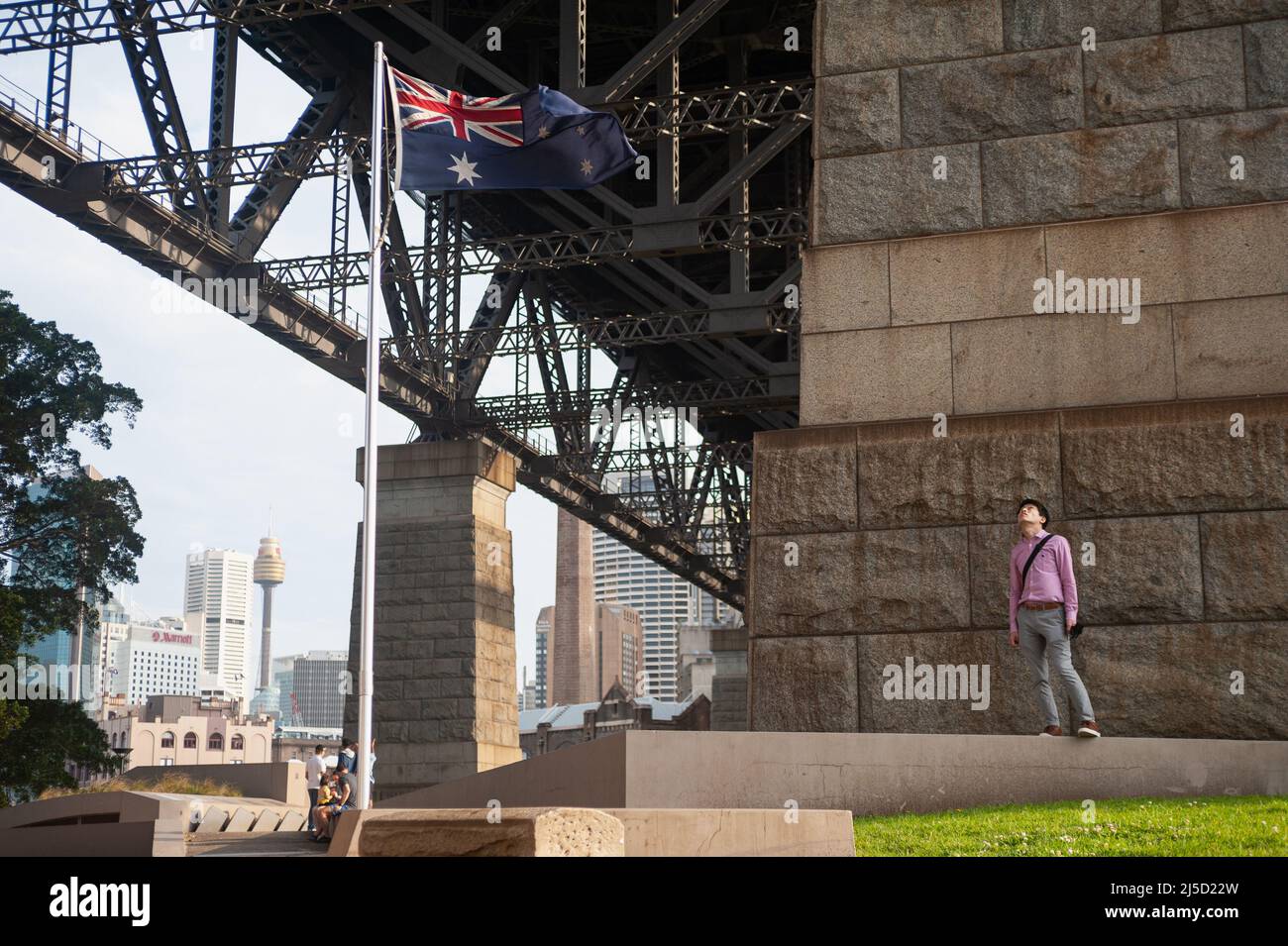 21. September 2019, Sydney, New South Wales, Australien - Ein Mann steht neben einer winkenden australischen Flagge unter der Sydney Harbour Bridge mit der Skyline des Geschäftsviertels und dem Sydney Tower im Hintergrund. [Automatisierte Übersetzung] Stockfoto