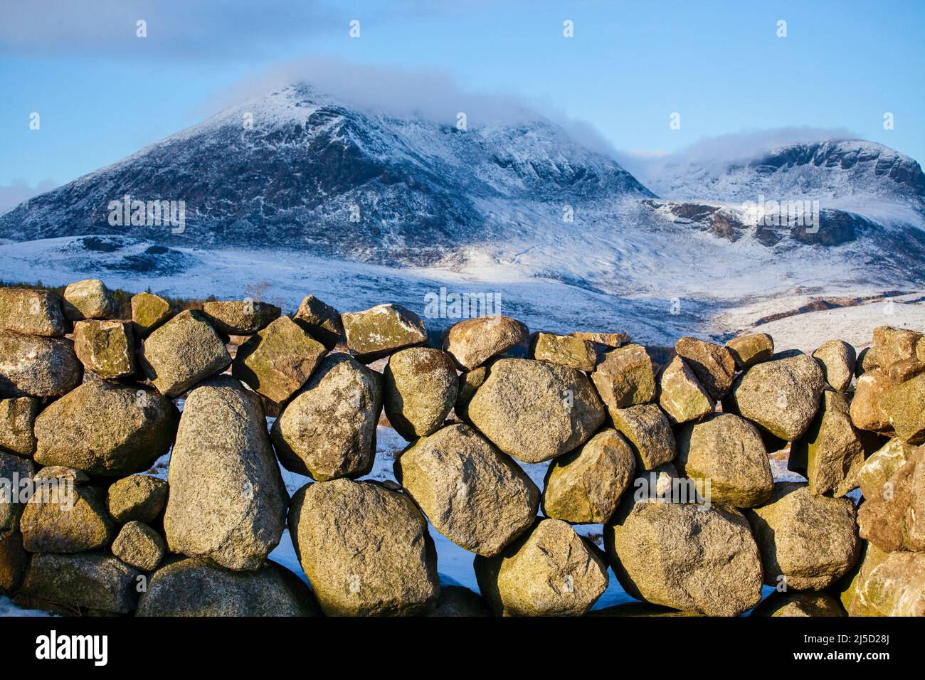 Eine Trockensteinmauer mit den Mournes im Schnee, County Down, Nordirland Stockfoto