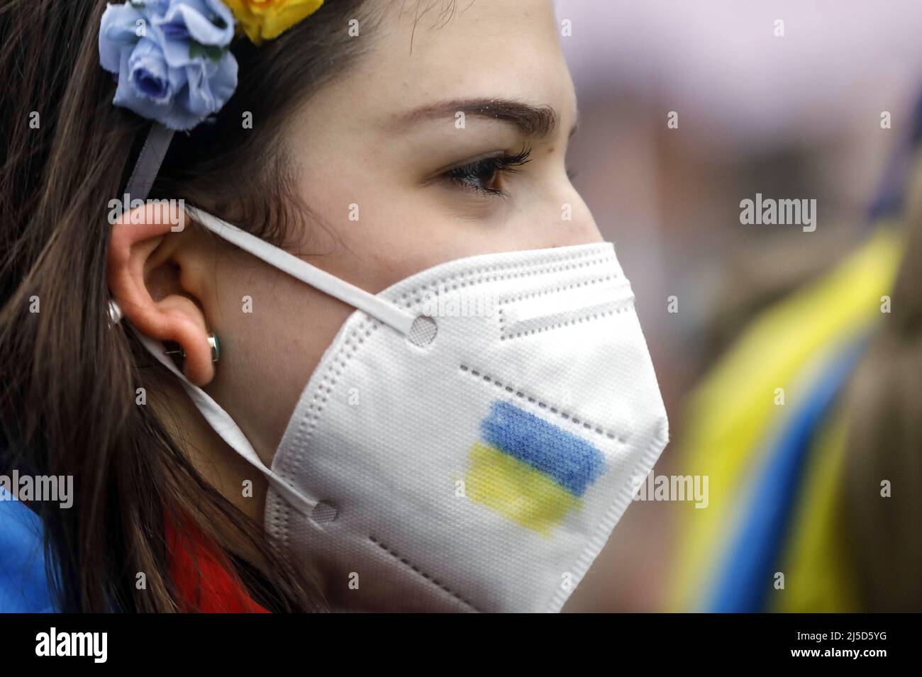 Berlin, 25. Februar 2022 - Ein ukrainischer Demonstranten trägt einen Blumenkranz und eine FFP2-er Maske mit den Farben der ukrainischen Flagge während einer Demonstration von Ukrainern nach dem russischen Angriff auf die Ukraine. [Automatisierte Übersetzung] Stockfoto