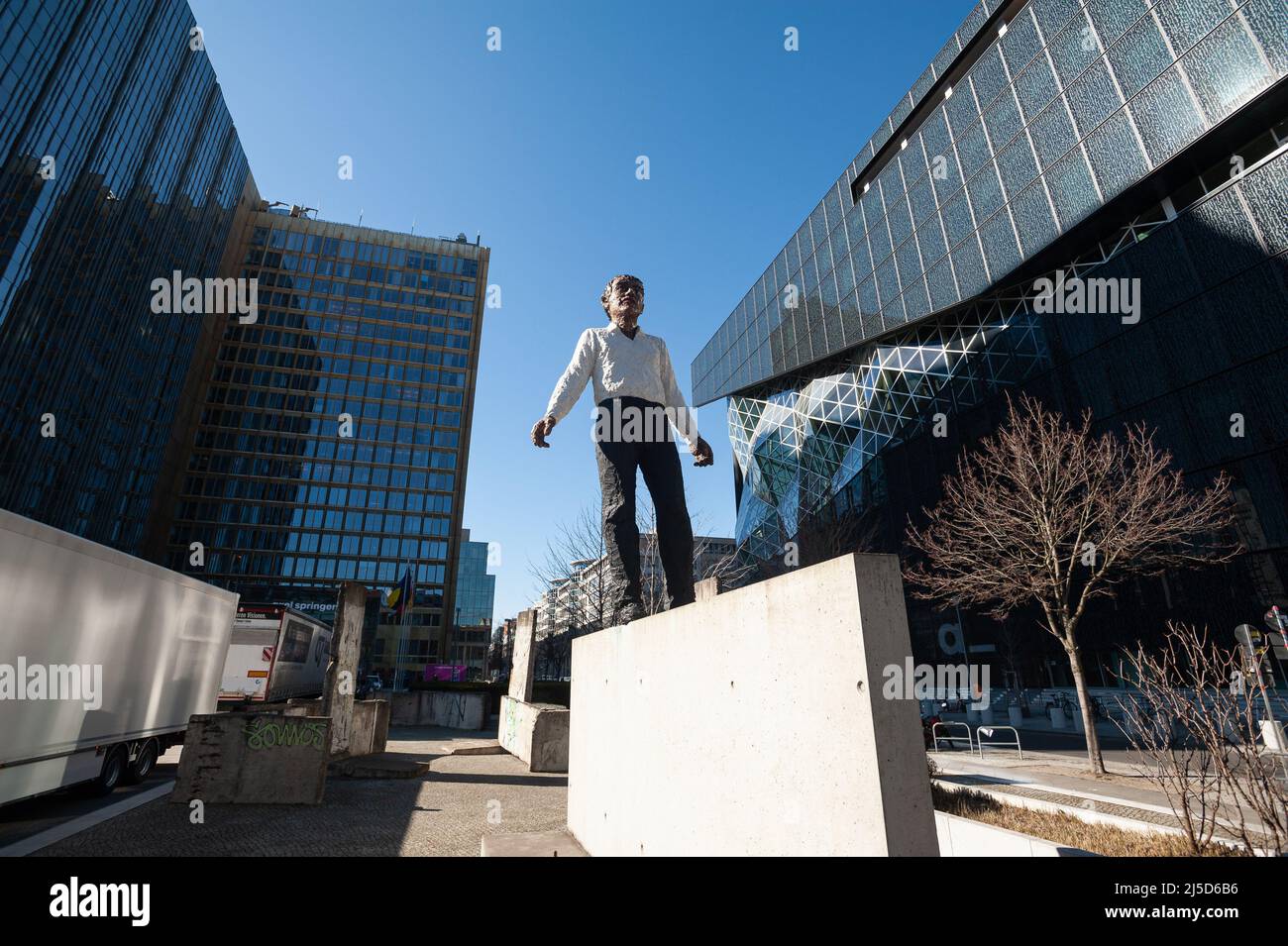 '03/12/2022, Berlin, Deutschland, Europa - die Skulptur ''Balanceakt'' ist ein Werk des deutschen Bildhauers Stephan Balkenhol und steht vor dem Axel Springer Wolkenkratzer und dem Neubau an der Ecke Axel-Springer-Straße und Zimmerstraße im Berliner Bezirk Kreuzberg. Die Arbeit besteht aus einem Mann mit schwarzer Hose und einem weißen Hemd, der auf einem Stück der Berliner Mauer balanciert, sowie elf Originalteilen der Mauer, die um die Figur platziert sind. Das Denkmal soll an die deutsche Wiedervereinigung und insbesondere den Fall der Mauer erinnern. [Automatisierte Übersetzung]' Stockfoto