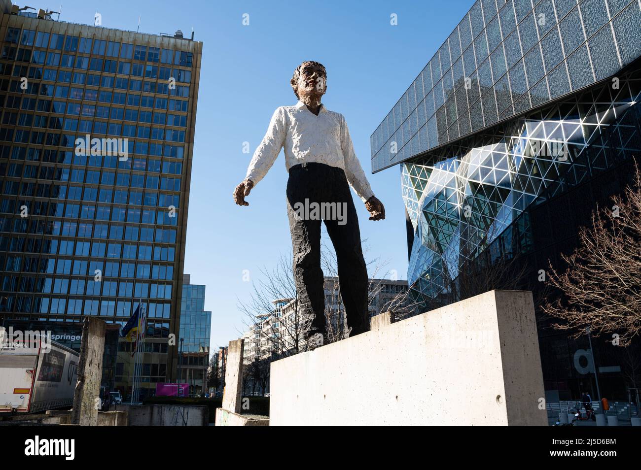 '03/12/2022, Berlin, Deutschland, Europa - die Skulptur ''Balanceakt'' ist ein Werk des deutschen Bildhauers Stephan Balkenhol und steht vor dem Axel Springer Wolkenkratzer und dem Neubau an der Ecke Axel-Springer-Straße und Zimmerstraße im Berliner Bezirk Kreuzberg. Die Arbeit besteht aus einem Mann mit schwarzer Hose und einem weißen Hemd, der auf einem Stück der Berliner Mauer balanciert, sowie elf Originalteilen der Mauer, die um die Figur platziert sind. Das Denkmal soll an die deutsche Wiedervereinigung und insbesondere den Fall der Mauer erinnern. [Automatisierte Übersetzung]' Stockfoto