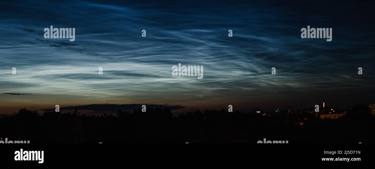 Nächtliche mesosphärische Wolken am Nachthimmel. Seltenes atmosphärisches Phänomen über der Stadt. Astronomie und Meteorologie. Bannerformat. Stockfoto