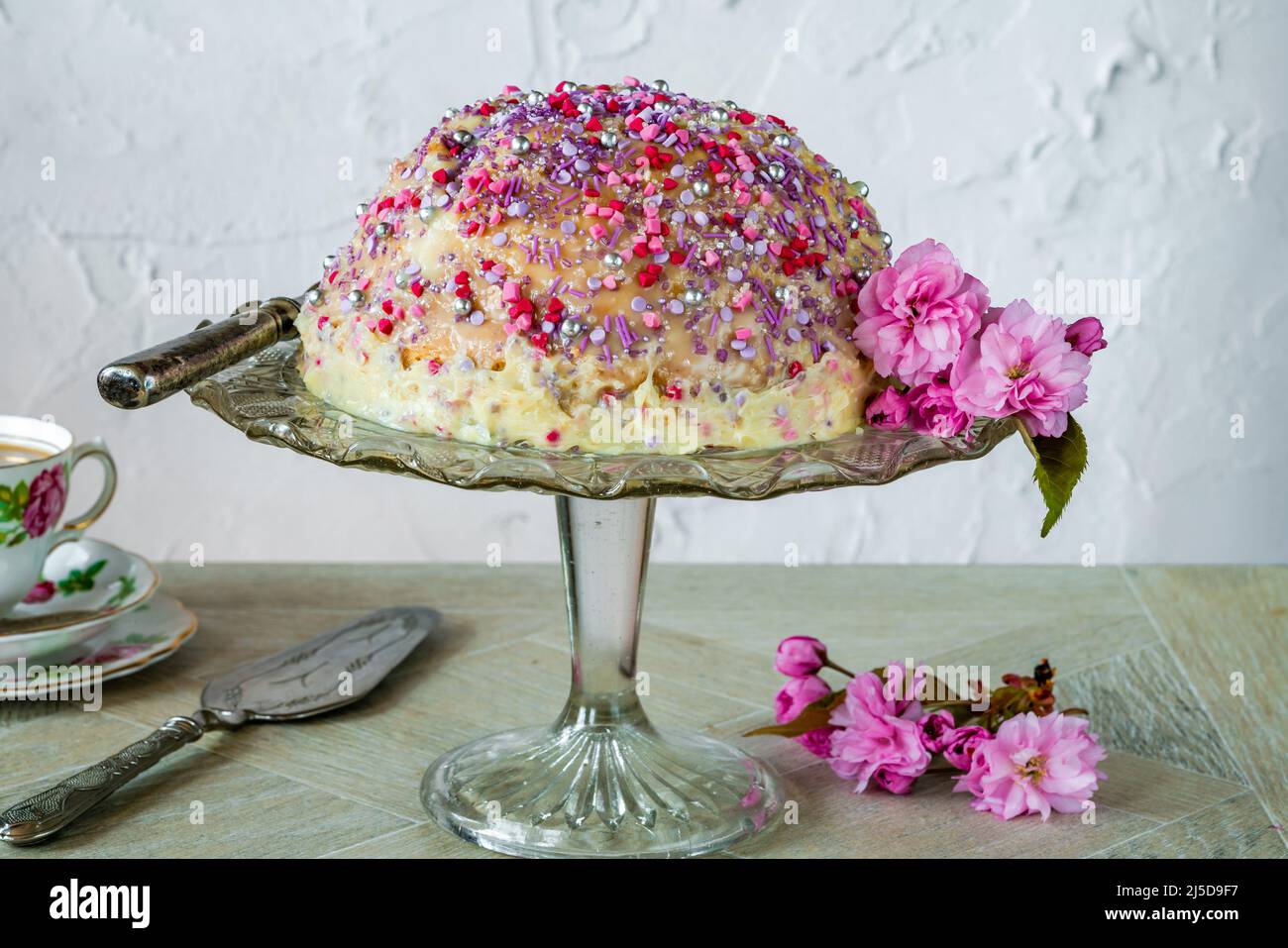 Kuchenkuchen - gefüllt mit fruchtigem Gelee, dunkler Schokoladenmousse und Himbeerpüree, überzogen mit weißer Schokoladenganache und verziert mit farbenfrohem Spri Stockfoto
