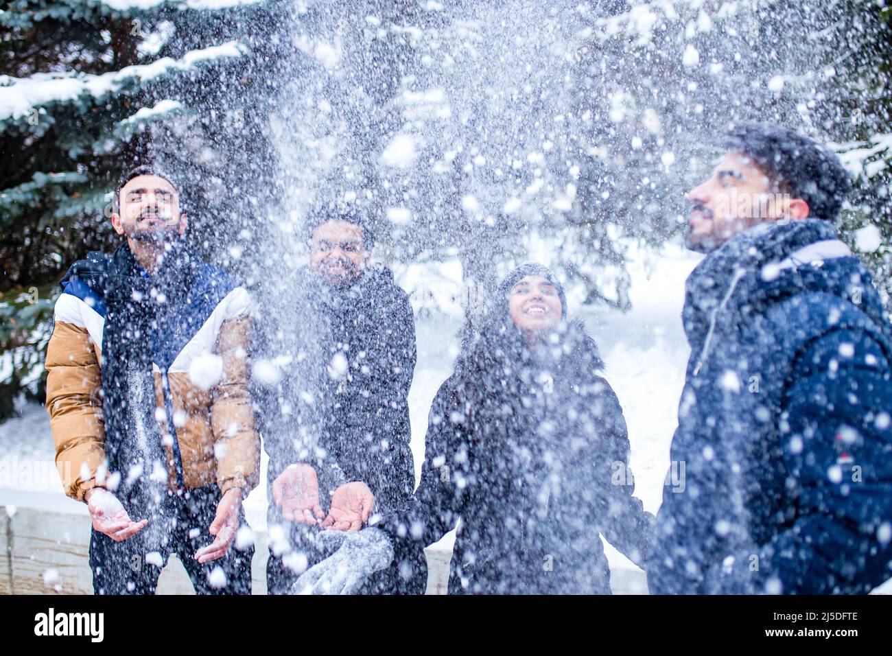 Eine Gruppe von vier indern, die Spaß beim Spielen im Schnee haben und Weihnachten im Freien verbringen Stockfoto