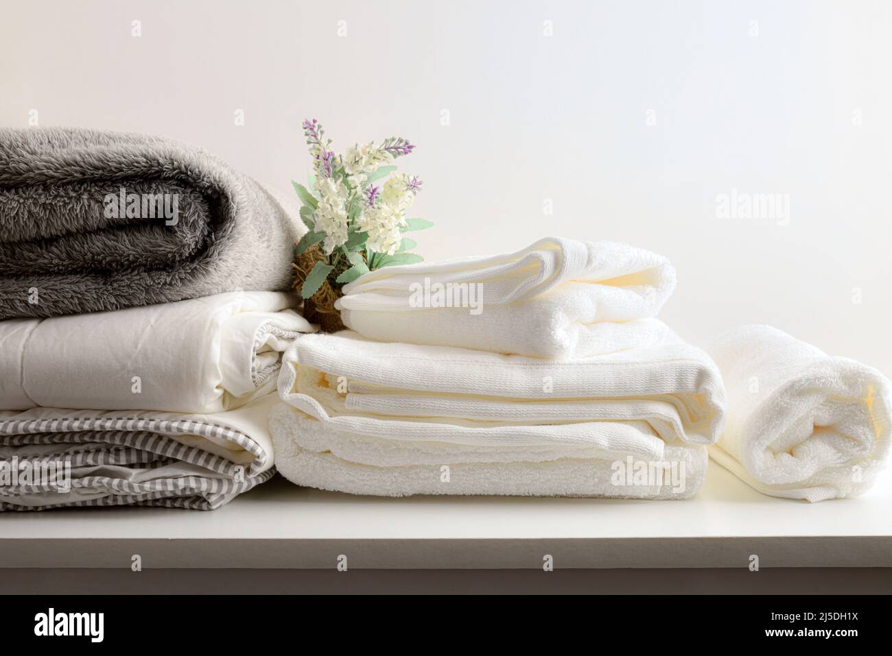 Saubere Bettwäsche und Handtücher auf Holzbank und weißer isolierter Hintergrund. Konzept der Kleiderreinigung. Vorderansicht. Horizontale Zusammensetzung. Stockfoto
