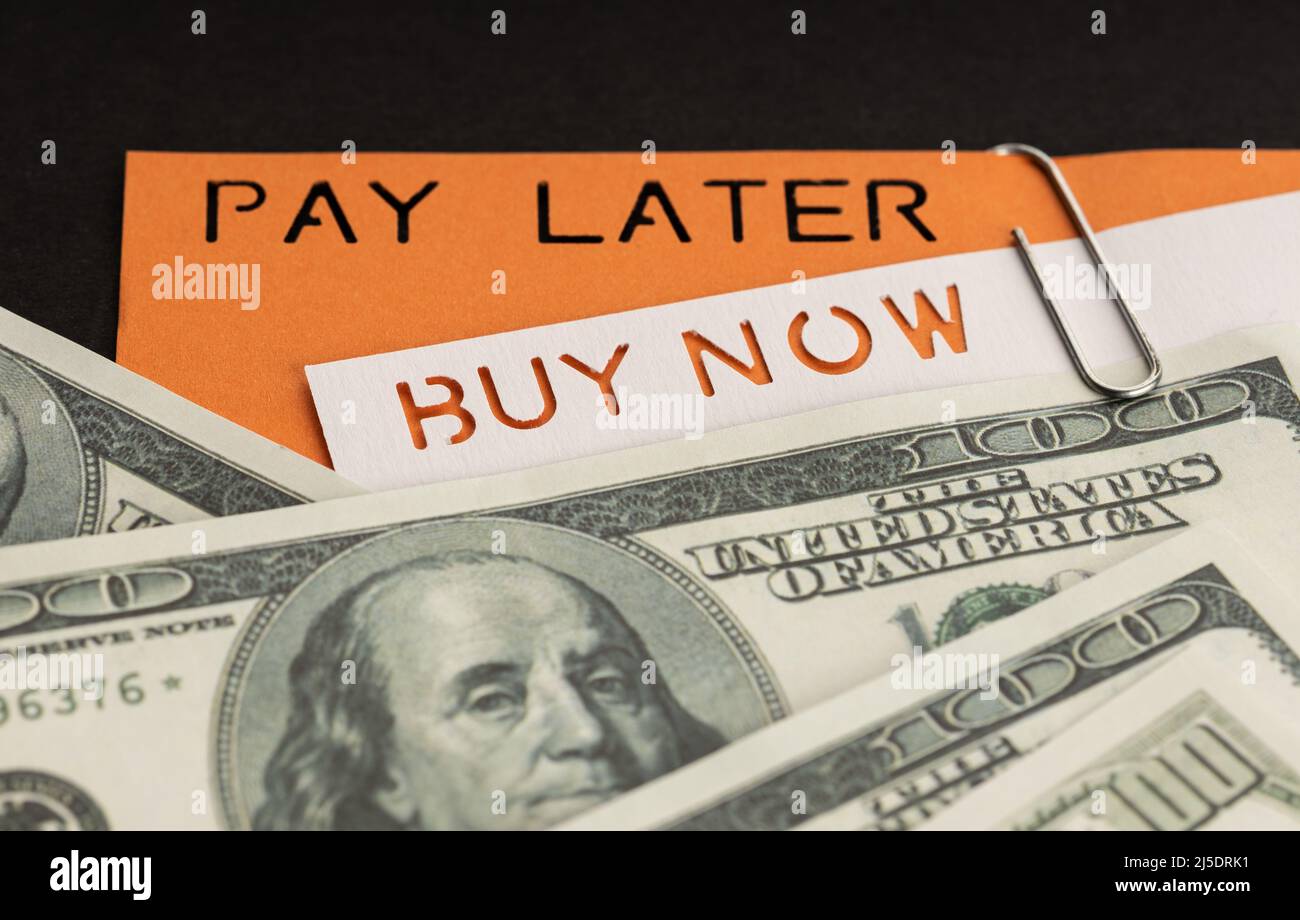 BNPL oder Buy Now Pay Later Concept. Dollarscheine und Etikett mit Botschaft auf schwarzem Hintergrund Stockfoto